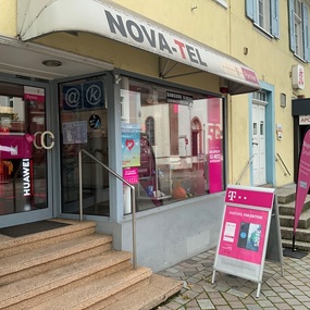 Eingang eines Mobilfunk- und Telekommunikationsshops mit Werbetafeln für Handytarife.